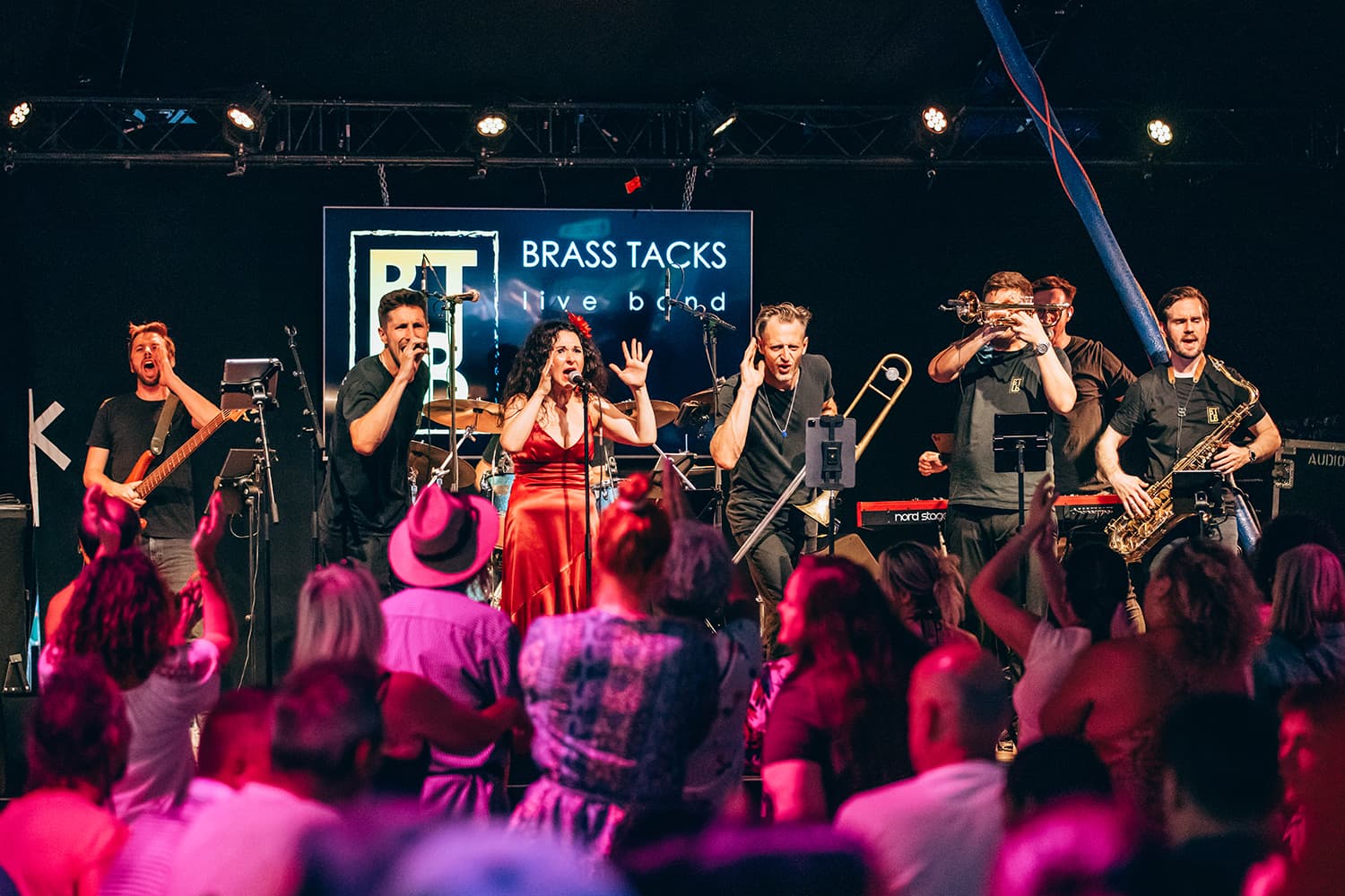 Brass Tacks Live Band firing up the dance floor, the crowd dancing with hands raised